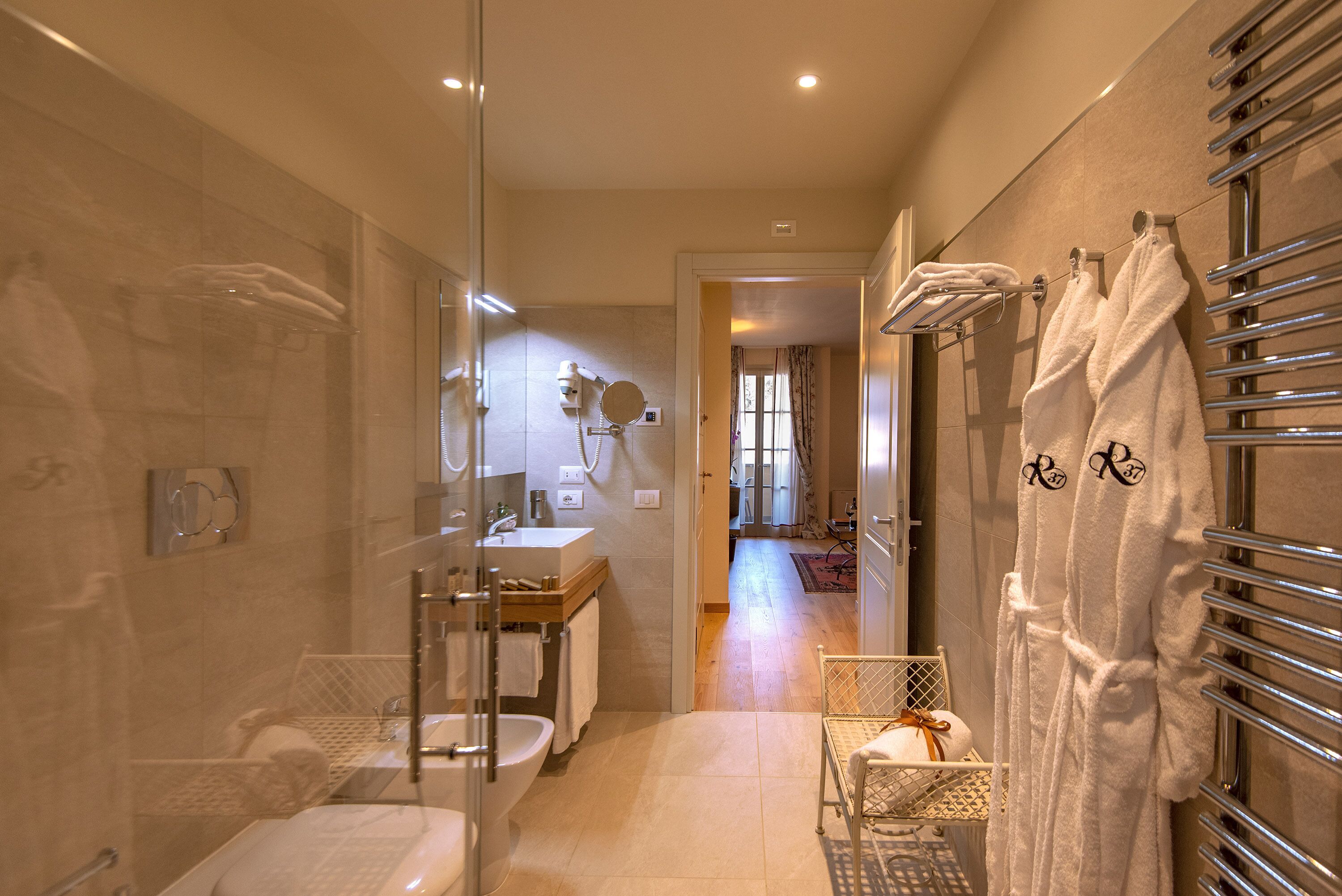 Une salle de bain moderne avec une douche à parois de verre, un lavabo et un porte-serviettes avec des peignoirs.