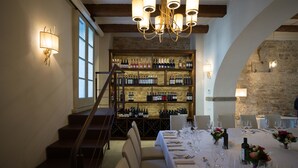 Un coin repas avec une longue table dressée pour le repas, un meuble à vin en arrière-plan et un escalier menant à un autre niveau.