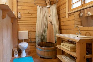 A wooden cabin bathroom with a toilet, sink, and wooden bucket. - Blockhaus Schwarzwald Hütte (Schenkenzell)