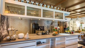A modern kitchen with a marble countertop, white cabinetry, and a glass-fronted upper shelf holding bottles. - Herrenhaus im Hofgut Bärenschlössle (Freudenstadt)