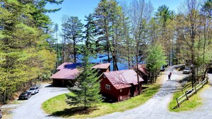 Une cabane avec un toit rouge, entourée d’arbres et bordée d’une allée de gravier.