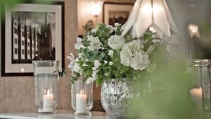 A table with a floral arrangement, candles, and a framed picture. - Cults Hotel (Aberdeen)
