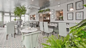 A restaurant with round tables, white chairs, and a large potted plant. - Cults Hotel (Aberdeen)