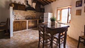 Une cuisine rustique avec des meubles de rangement en bois, un sol carrelé, une table à manger en bois avec des chaises et une fenêtre offrant une vue agréable.
