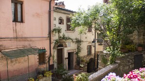 Une ruelle étroite bordée de bâtiments des deux côtés, avec des murs en pierre et des plantes en pot.