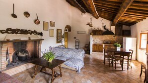 Une cuisine rustique avec une cheminée en briques, des poutres apparentes et un coin repas comprenant une table et des chaises.