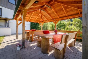 A wooden pavilion with a table and benches, surrounded by a brick patio and greenery. - Luxus Ferienhaus Feldberg (Feldberg)