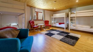 A room with bunk beds, a blue sofa, a red armchair, a small table, and a checkered rug.