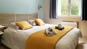A bedroom with a bed, pillows, a blanket, a radiator, and a window with curtains. - L'ARENE Cassis Centre - T2 comfortable quiet 100m beach 4.5 kms calanques (Cassis)