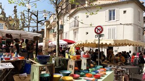 A bustling outdoor market with various stalls selling colorful bowls and other items. - L'ARENE Cassis Centre - T2 comfortable quiet 100m beach 4.5 kms calanques (Cassis)