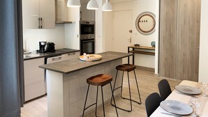 A modern kitchen with a central island, bar stools, and pendant lighting. - L'ARENE Cassis Centre - T2 comfortable quiet 100m beach 4.5 kms calanques (Cassis)