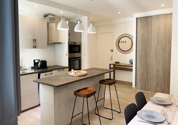A modern kitchen with a central island, bar stools, and pendant lighting.