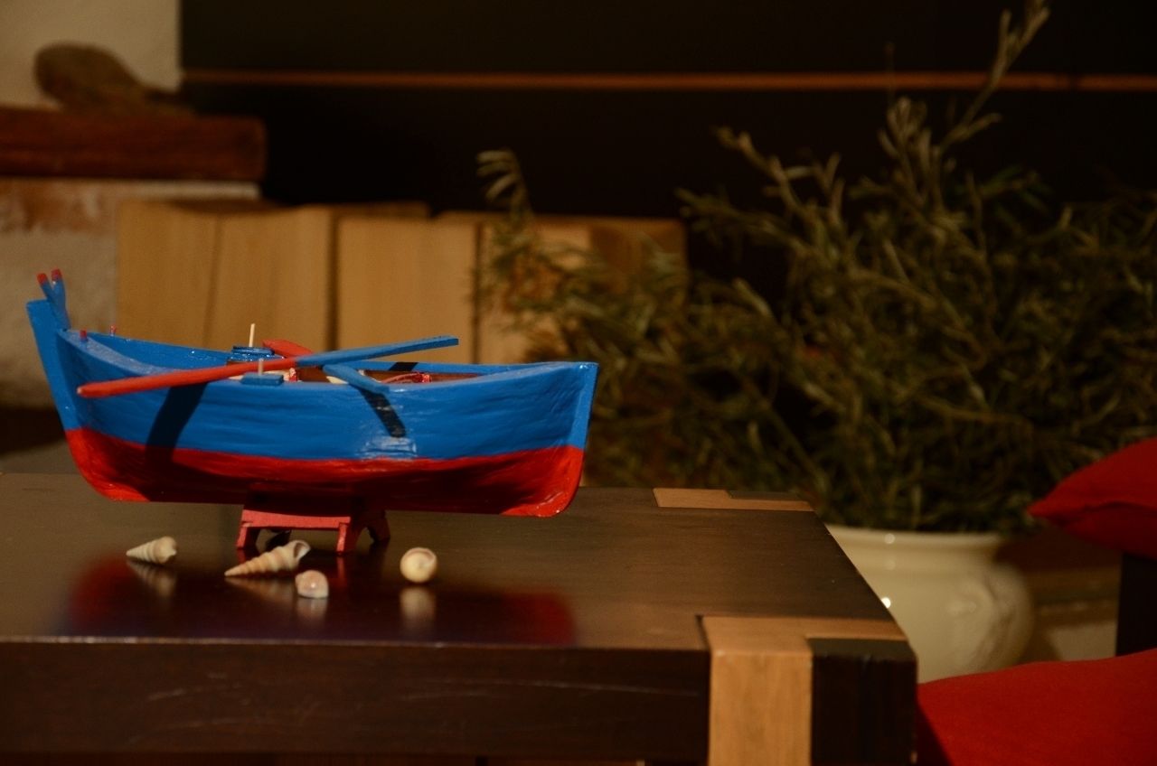A model boat on a table with a potted plant in the background.