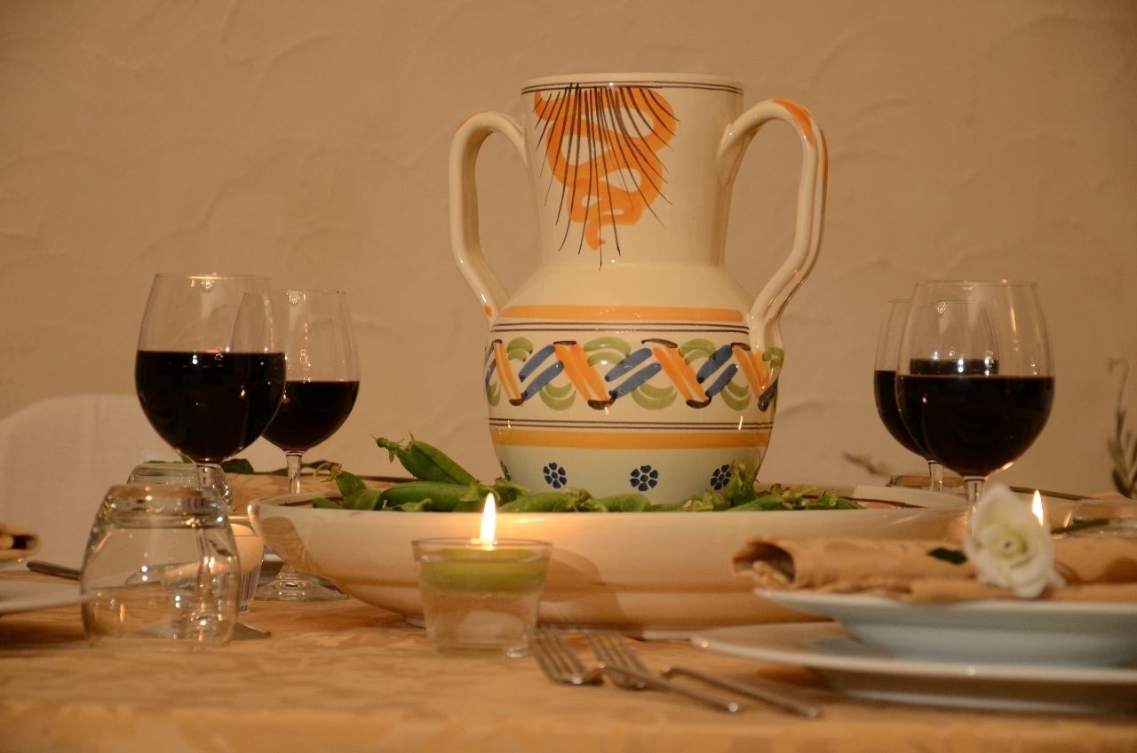 A dining table set with a pitcher, glasses, a candle, and a plate with food.