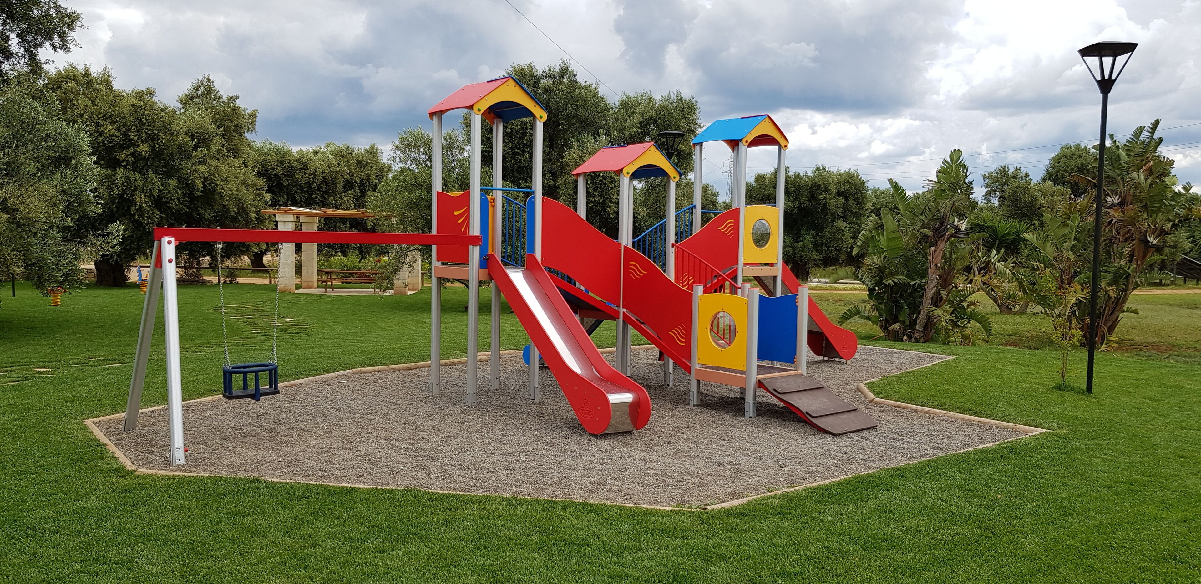 Ein Spielplatz mit einer roten Rutsche, Klettergerüsten und einer Schaukel.