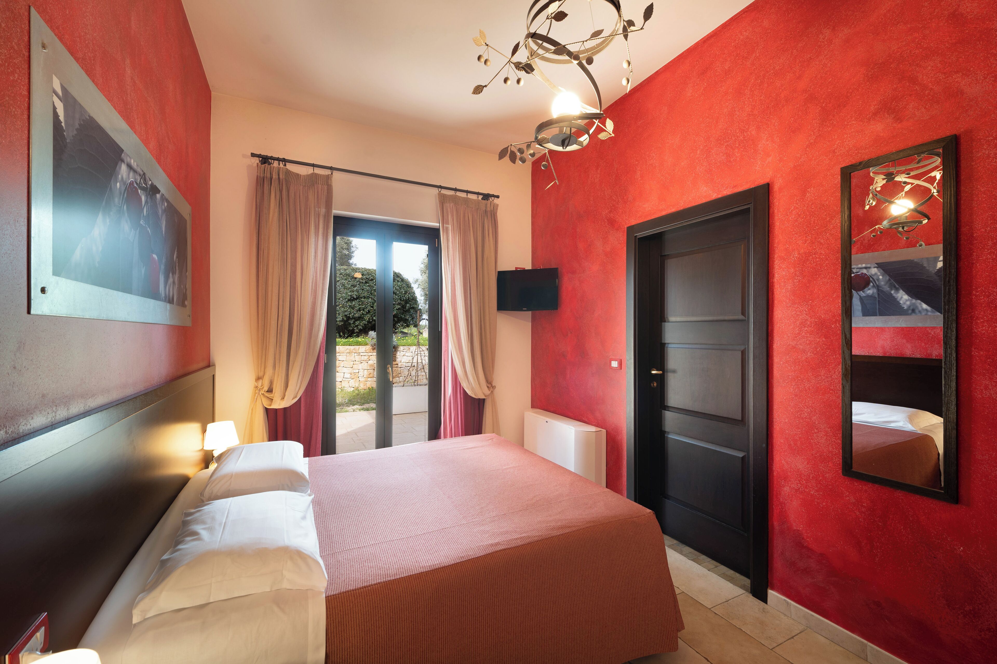 A hotel room with a bed, a TV, a door, and a window with curtains.