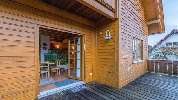 Une cabane en bois dotée d’un patio couvert, d’un coin repas avec des chaises et une table, et d’un appareil de cuisine de couleur verte.