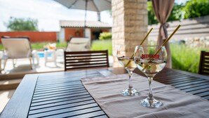Two glasses of wine on a table with a view of outdoor seating and a pool. - Stylish villa ****, pool, 2.5 km from the sea, barbecue, WiFi, free WiFi (Segotici)