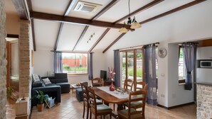 A spacious living area with a dining table, chairs, and a sofa. There is a kitchen area with a microwave and a stone wall. - Stylish villa ****, pool, 2.5 km from the sea, barbecue, WiFi, free WiFi (Segotici)