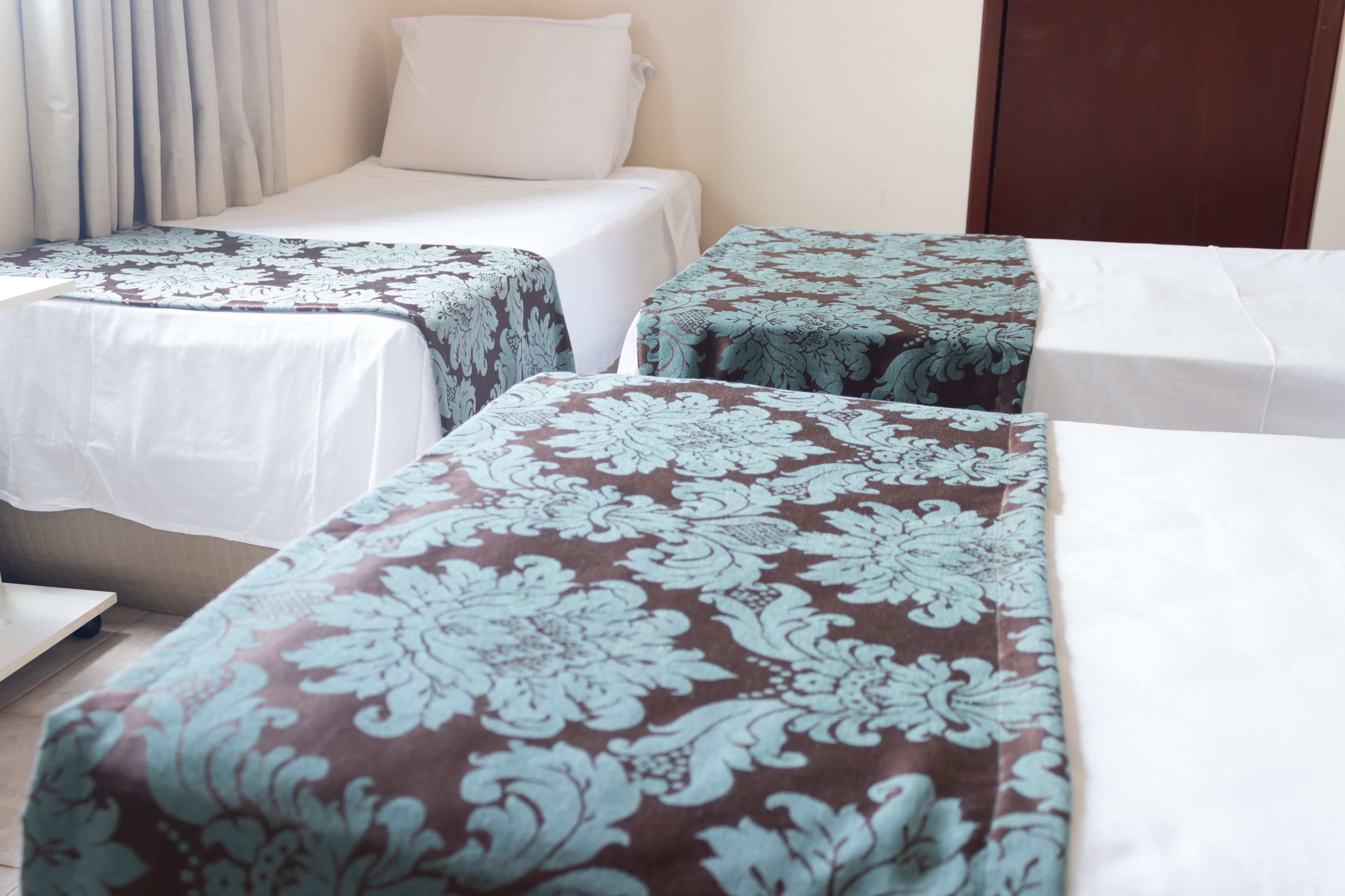 A hotel room with two single beds, each with a patterned bedspread.