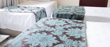 A hotel room with two single beds, each with a patterned bedspread.