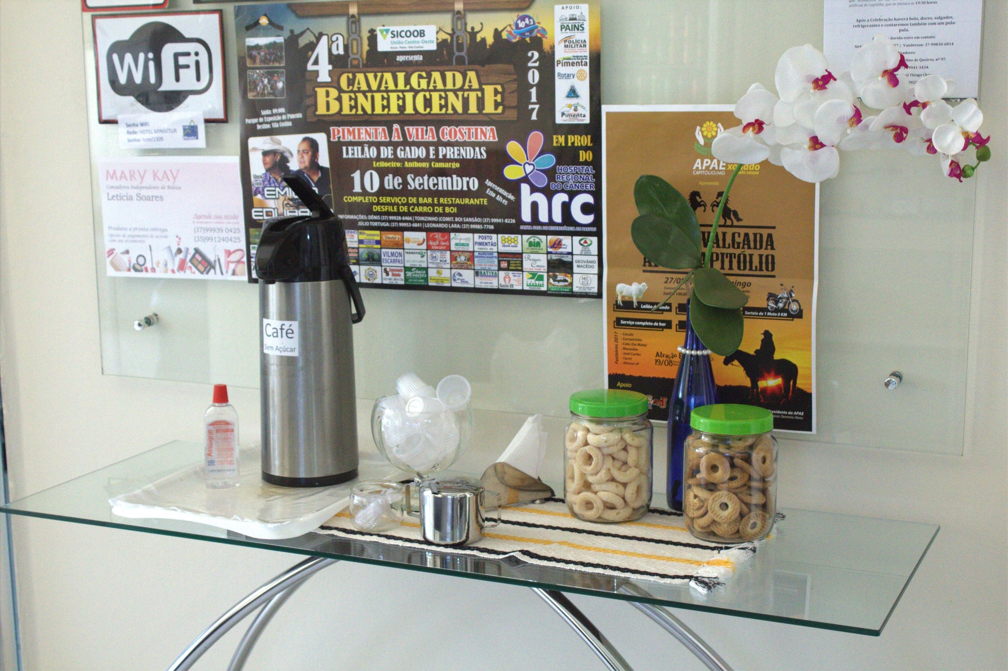 Una mesa de vidrio con una cafetera, recipientes de aperitivos y un letrero de Wi-Fi.