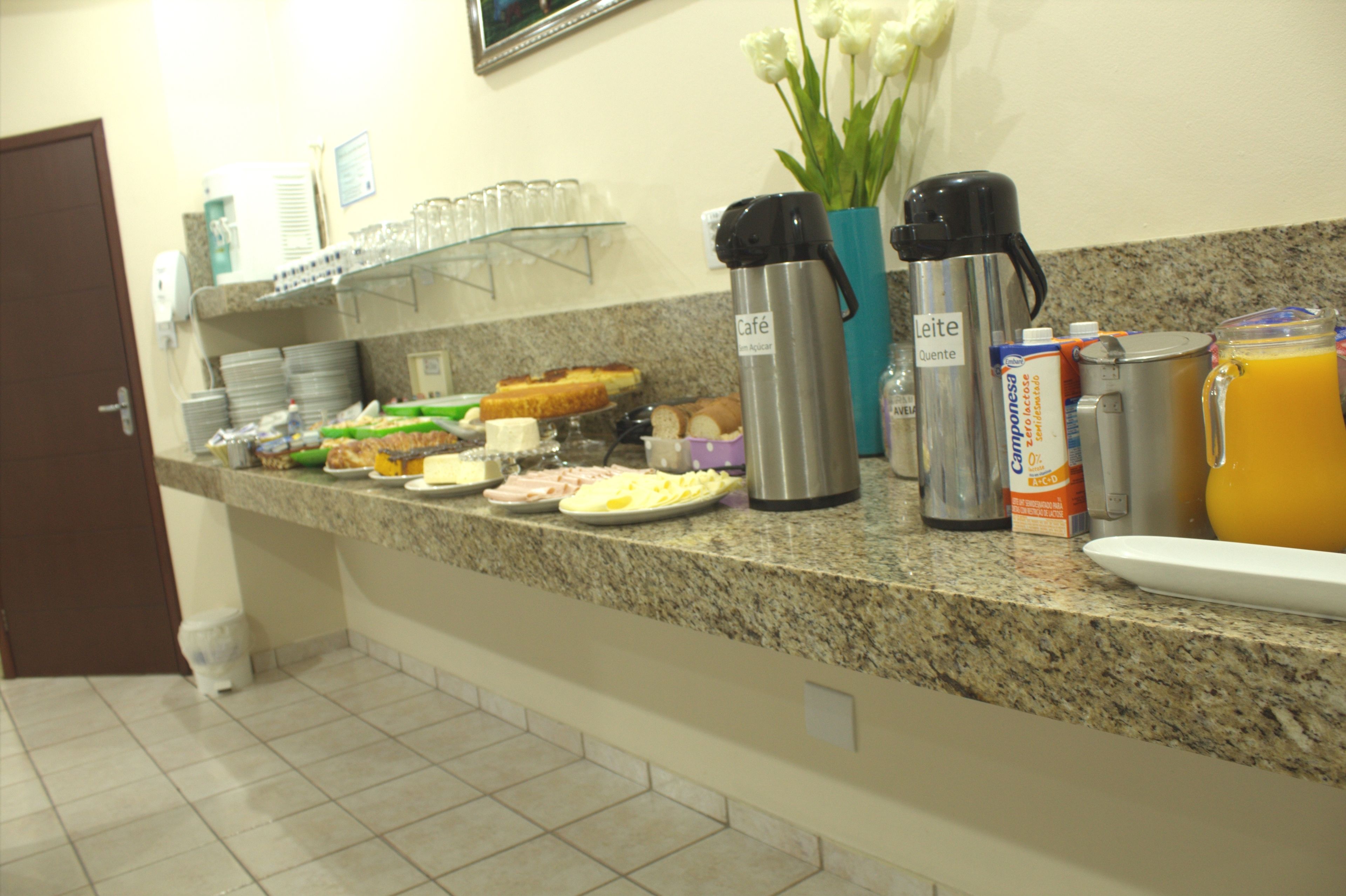 Un bufé de desayuno con diversas opciones de alimentos, cafeteras y un dispensador de zumo.