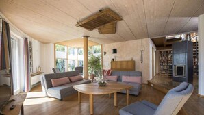 A spacious living room with a wooden ceiling, a round wooden coffee table, a grey sofa, and a blue armchair. - Ferienhaus Dornstetten (Dornstetten)