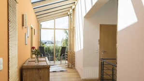 A hallway with a wooden desk, chairs, and a view of greenery outside. - Ferienhaus Dornstetten (Dornstetten)