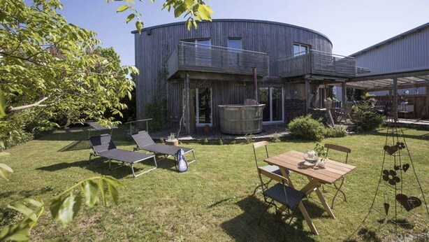 A modern house with a curved exterior, a balcony, and a large wooden barrel. - Ferienhaus Dornstetten (Dornstetten)