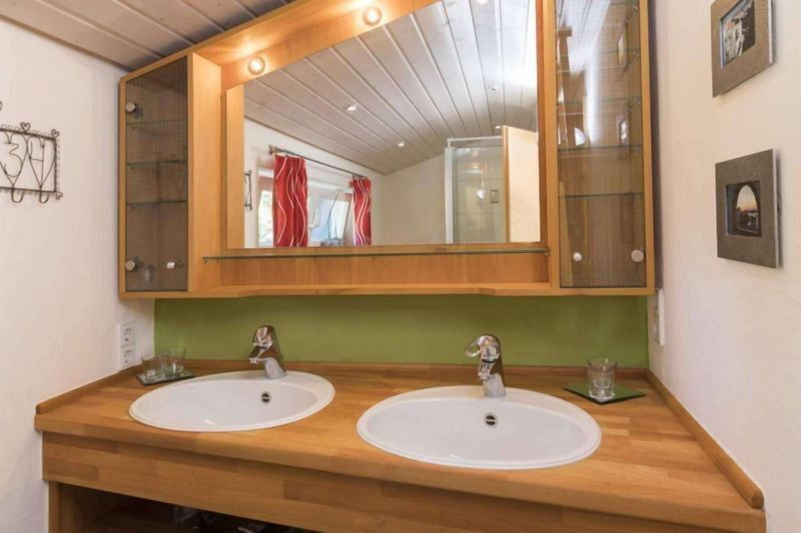 Ein Badezimmer mit zwei Waschbecken, einem großen Spiegel und einem hölzernen Waschtisch.