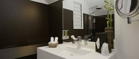 A modern bathroom with a white sink, a large mirror, and a shower.