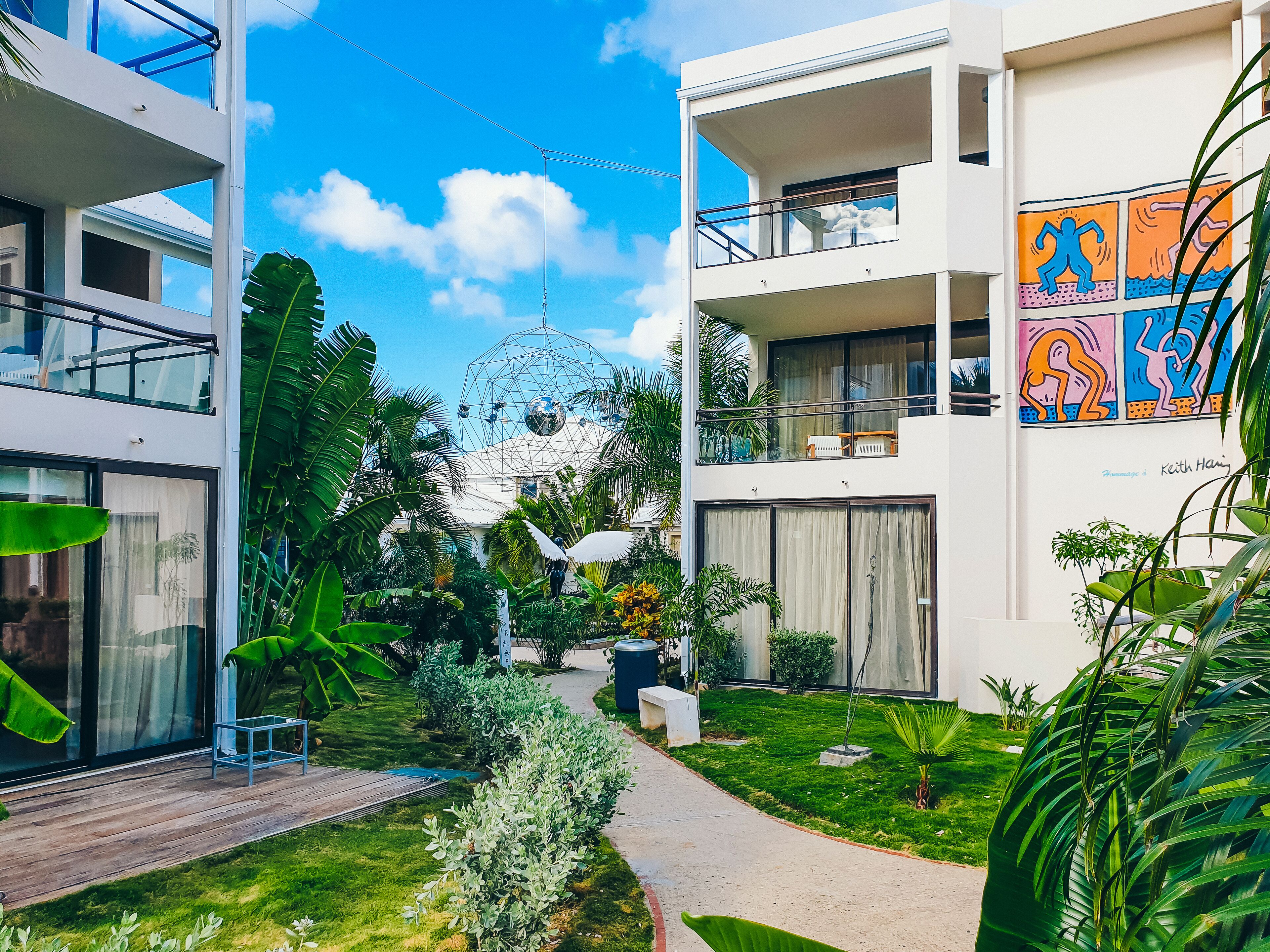 Un bâtiment moderne doté d’une façade en verre, d’un jardin sur le toit et d’une fresque colorée sur le mur extérieur.