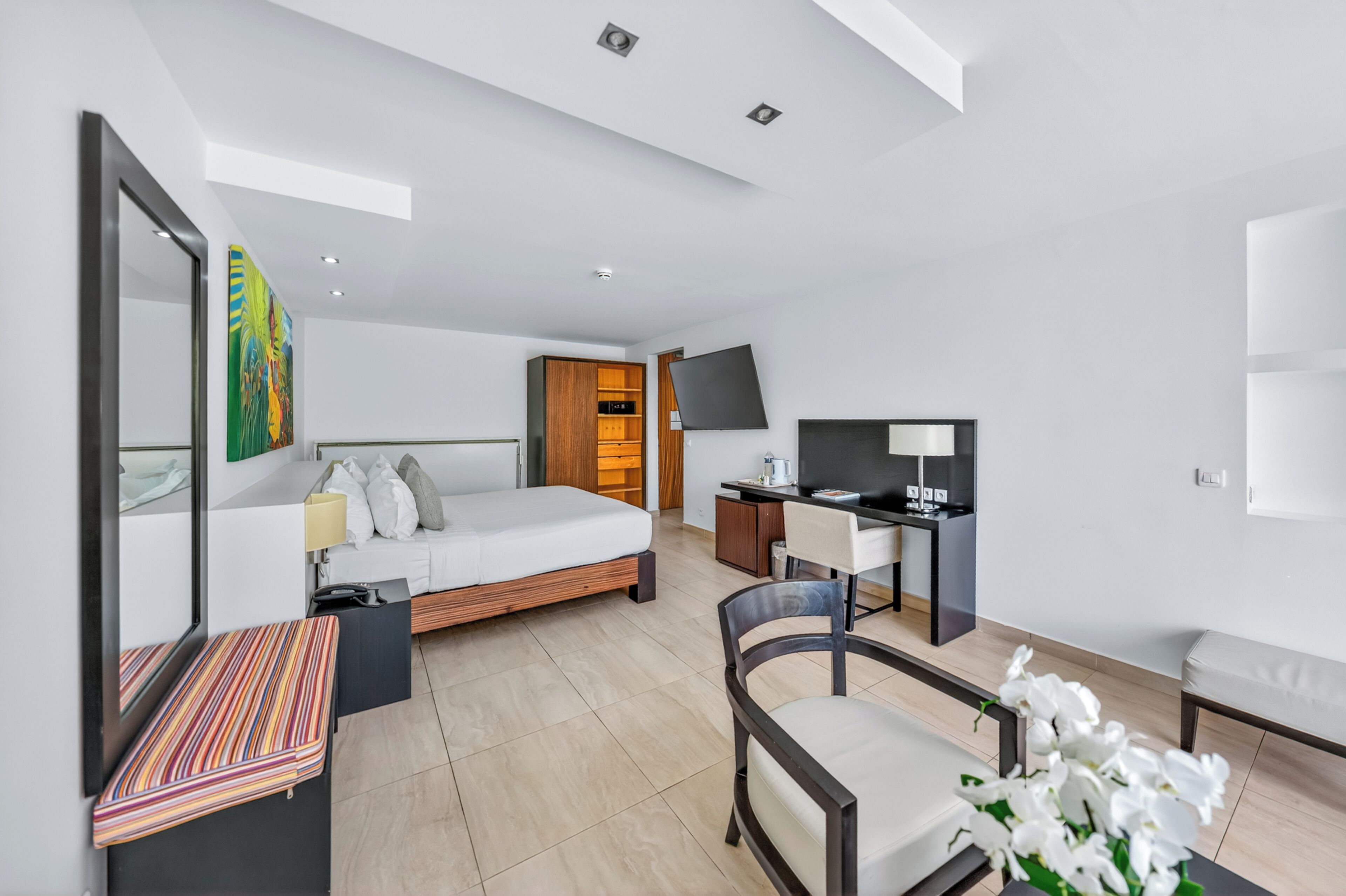 A modern hotel room with a bed, desk, chair, and a television.