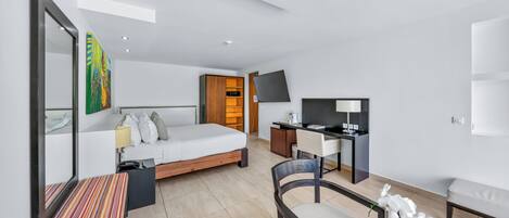 A modern hotel room with a bed, desk, chair, and a television.