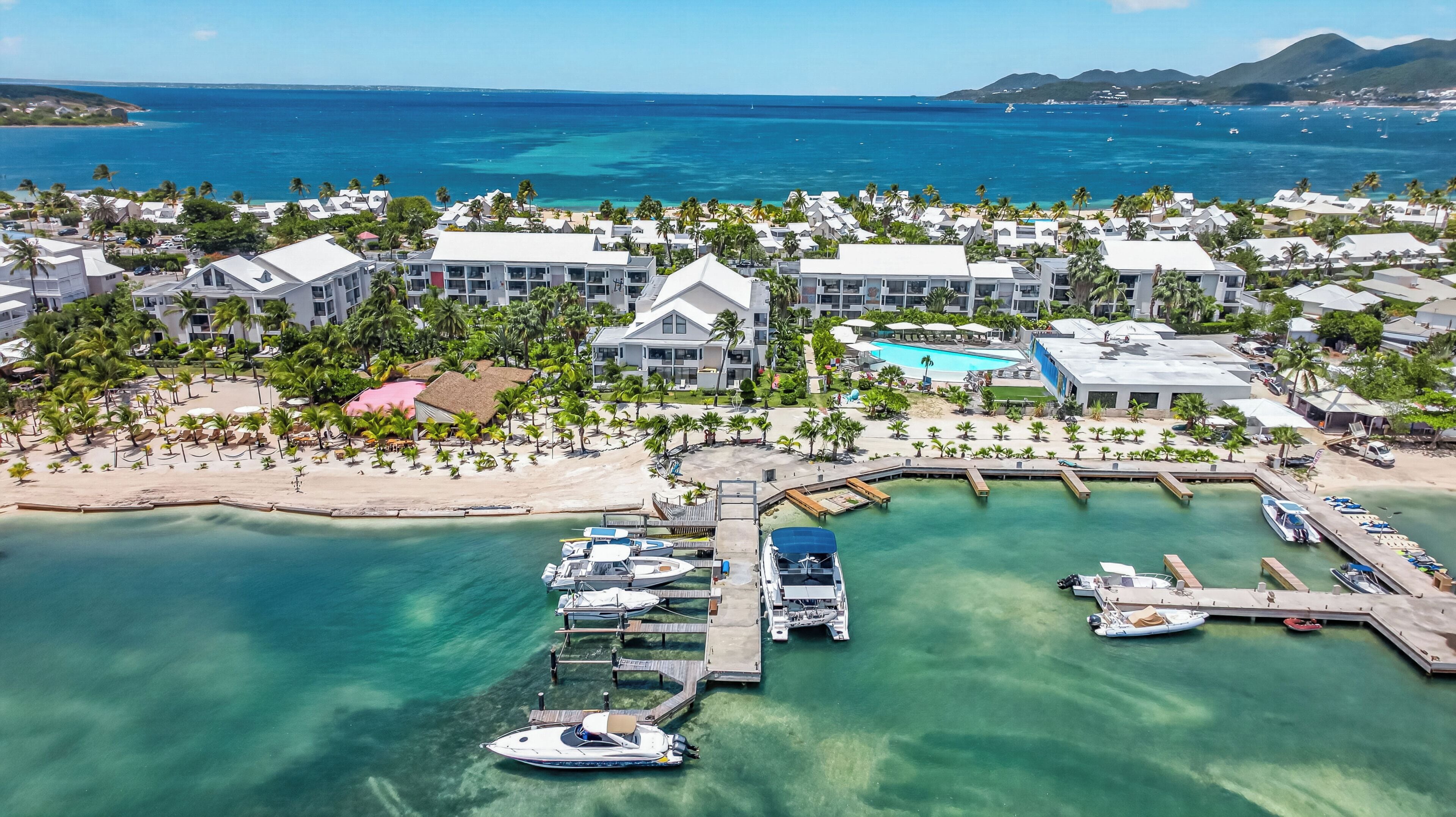 A coastal resort with multiple buildings, a marina, and clear turquoise waters.