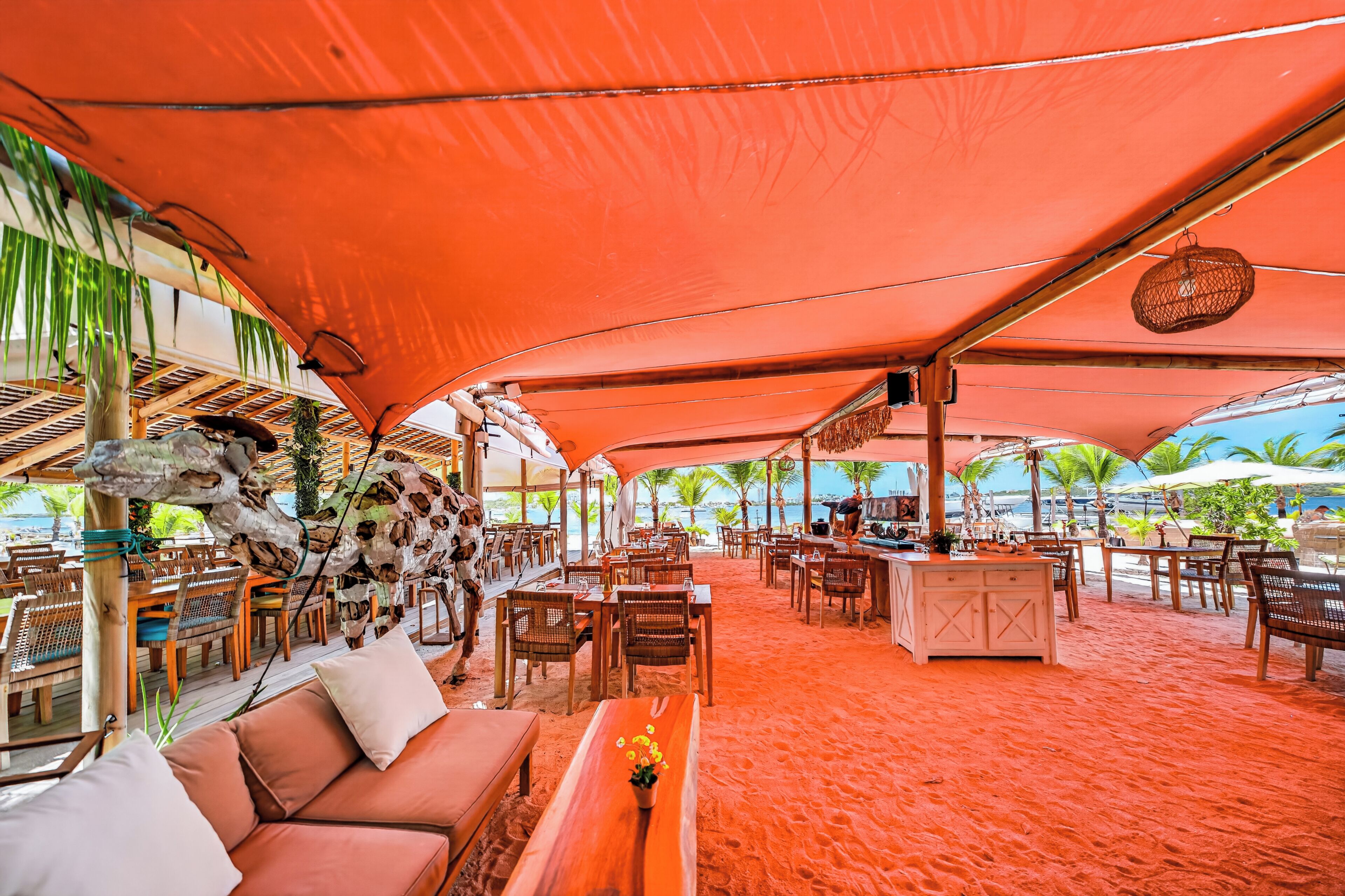 Un área de comedor al aire libre con mesas, sillas, un bar y vista al mar.