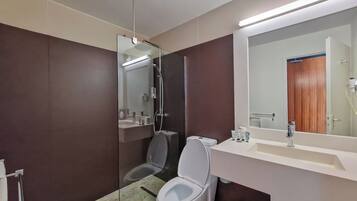A modern bathroom with a glass-enclosed shower, a white toilet, and a vanity with a mirror.