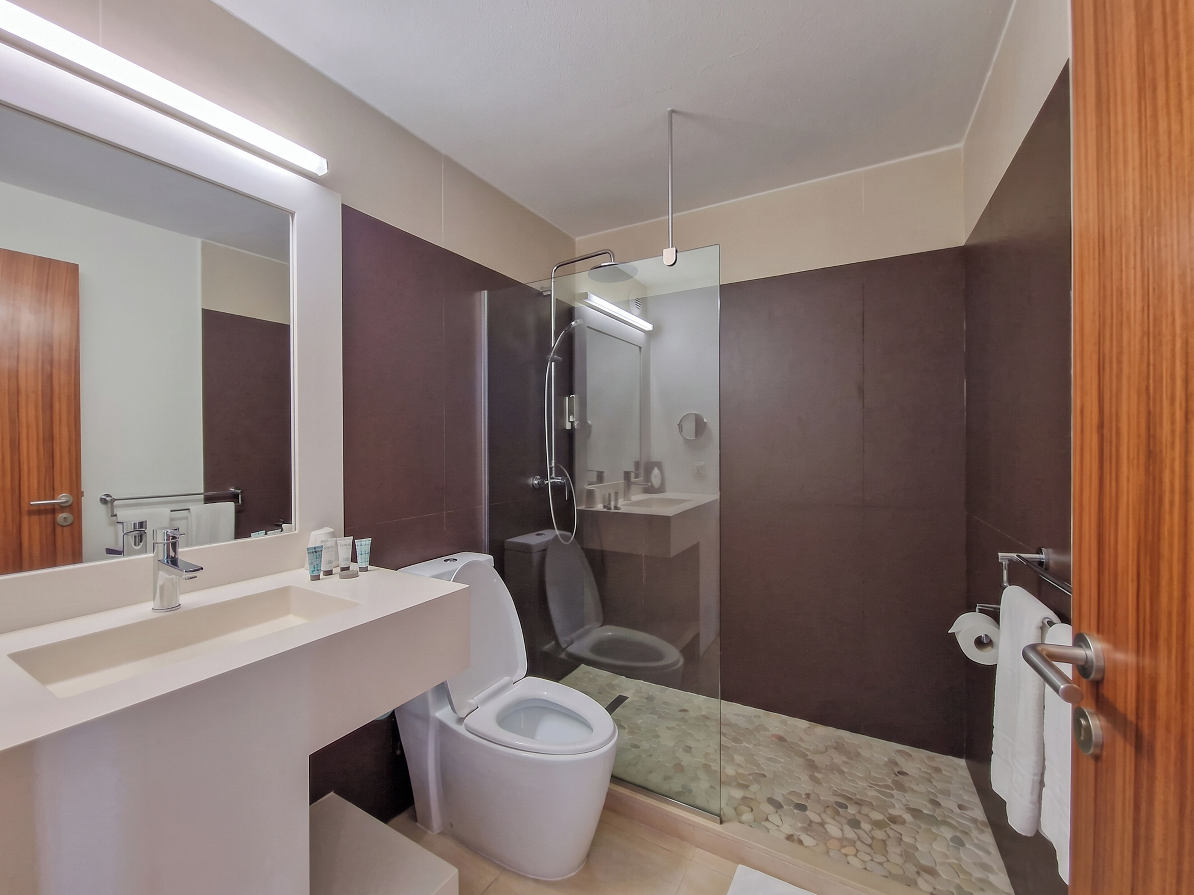 A modern bathroom with a glass-enclosed shower, a white sink, and a toilet.