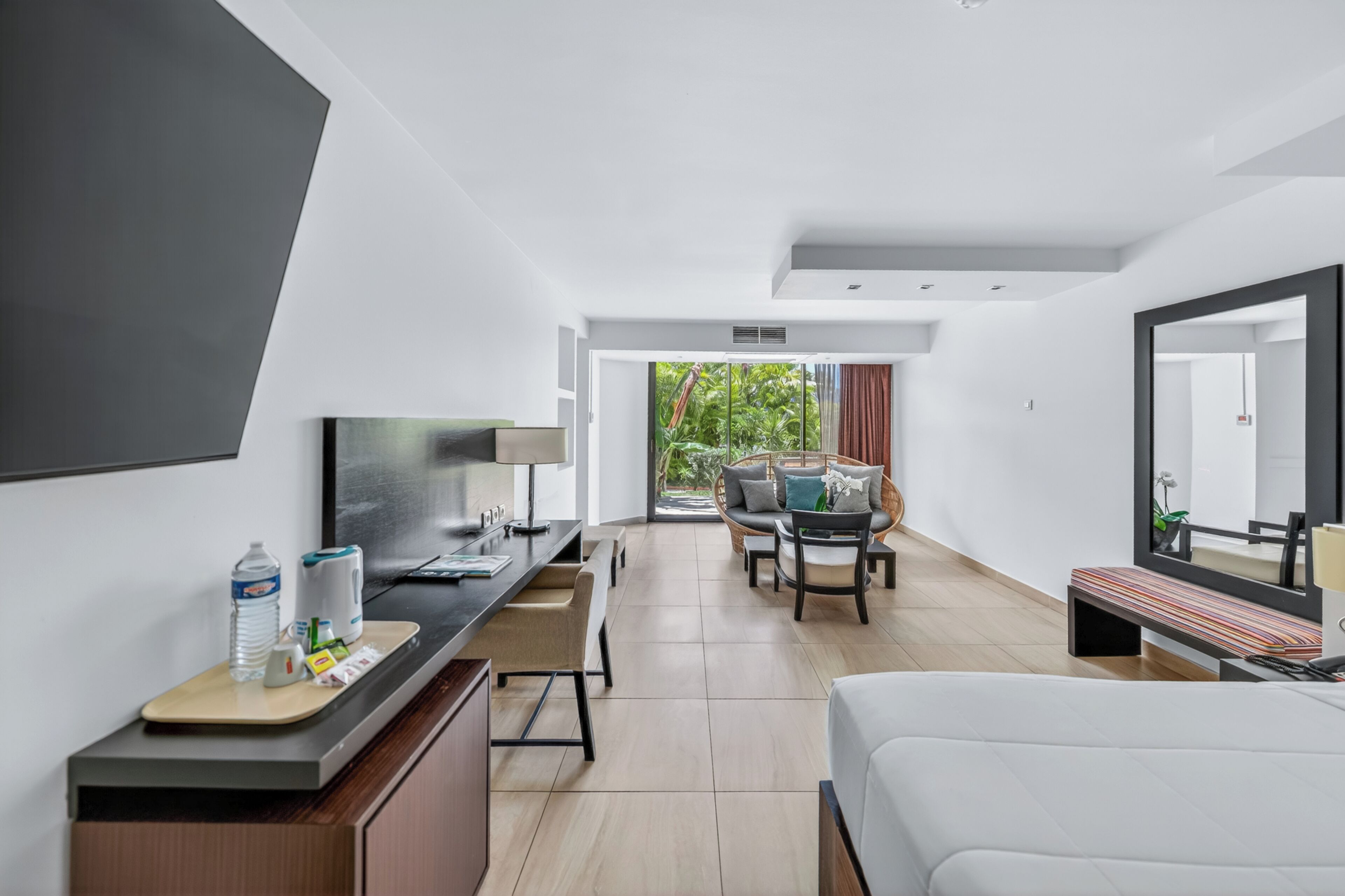 Una habitación de hotel moderna con cama, escritorio, silla y un espejo grande.