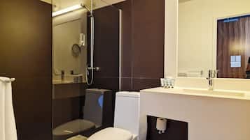 Un baño moderno con ducha de vidrio, inodoro y lavamanos con espejo.