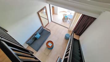 A modern interior with a staircase, a sofa, a round table, and a view of an outdoor area.