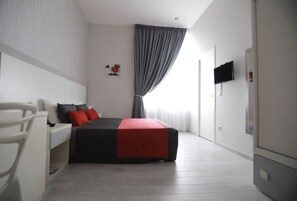 A modern bedroom with a bed, a desk, and a chair. - Chiaia Guest House (Naples)