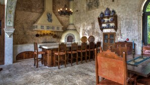 A rustic dining area with a stone wall, wooden chairs, a large table, and a traditional oven. - Stay in Mérida's Grand Colonial Mansion w/ Private Pool (Centro)