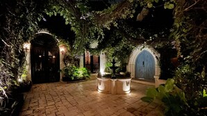 A paved courtyard with a fountain, surrounded by greenery and stone walls. - Stay in Mérida's Grand Colonial Mansion w/ Private Pool (Centro)