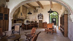 A rustic kitchen with wooden furniture, a stone oven, and a large arched doorway leading outside. - Stay in Mérida's Grand Colonial Mansion w/ Private Pool (Centro)