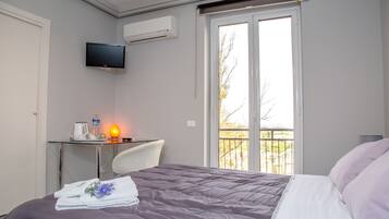 A hotel room with a bed, a desk with a chair, a television, and a window with a view of the outdoors.