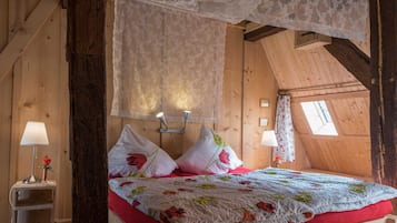 A cozy bedroom with a canopy bed, floral bedding, and a small bedside table with a lamp.