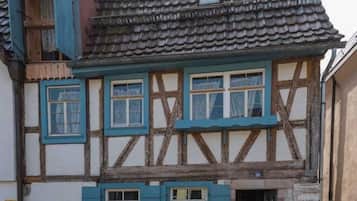 A traditional half-timbered house with a tiled roof, multiple windows with shutters, and a visible chimney.
