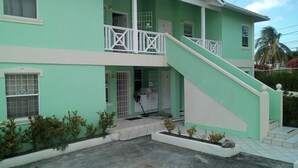 A two-story building with a green exterior, white railings, and a small front garden. - Winfort 4 Bay Walk (Gros Islet)